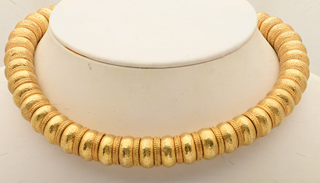 Ilias Lalaounis 18K Yellow Gold Bead Necklace resting on a display, exemplifying the artisanal quality and timeless elegance of luxury jewelry from Vivid Diamonds.