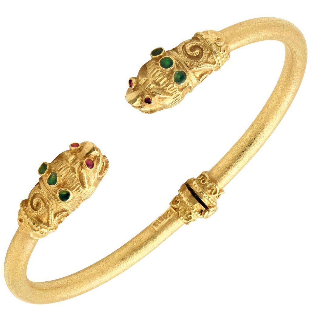 18K Yellow Gold Double Lion Cuff Bracelet with Ruby Eyes & Emerald Accents by Vivid Diamonds, featuring intricately sculpted lion heads adorned with vivid gemstones.